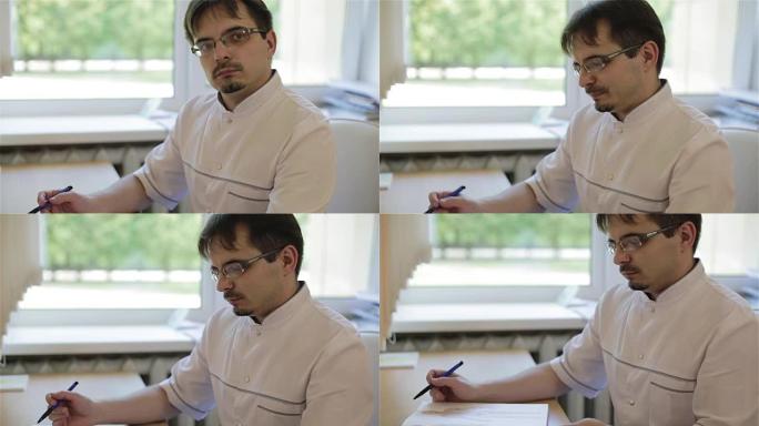 戴眼镜的医生坐在桌子旁，在文件中写字。