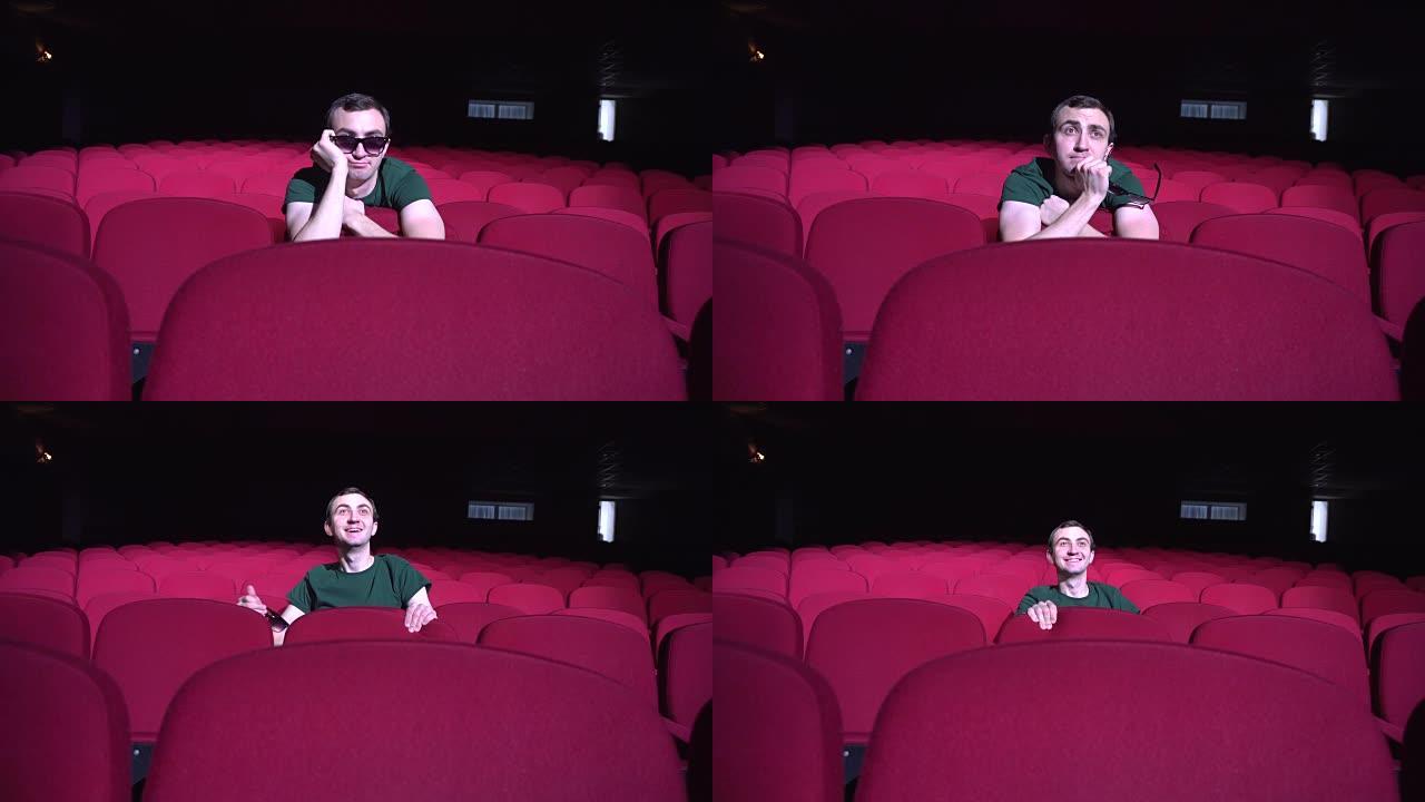 一个坐在黑暗电影院舒适的红色椅子上的男人看起来喜剧和笑声