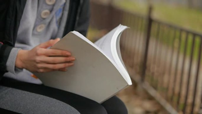 女性手拿着书和香烟的特写。女孩在公园户外学习女性教育。