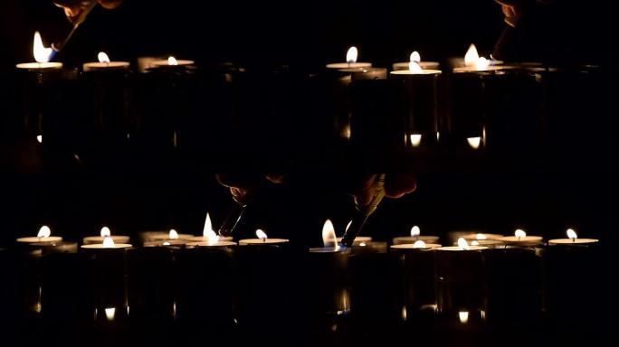 许多蜡烛在黑暗中燃烧。蜡烛被打火机点燃