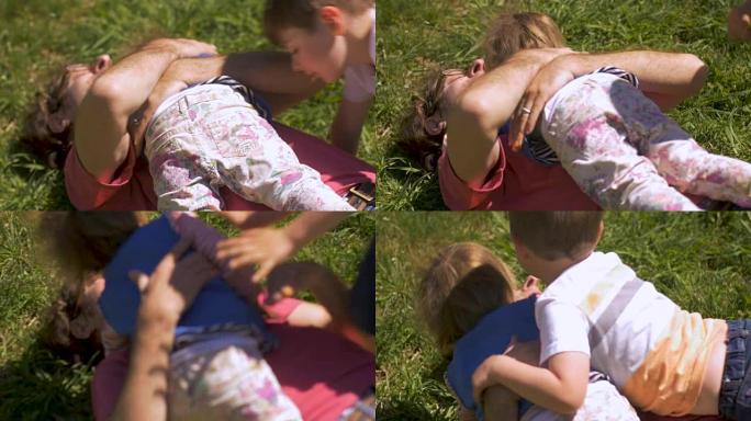 两个小孩在草地上摔跤时拥抱父亲