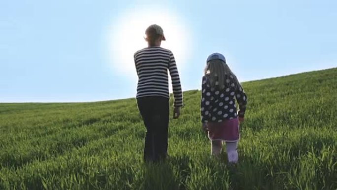 男孩和女孩在绿色草地上的灿烂阳光下行走。