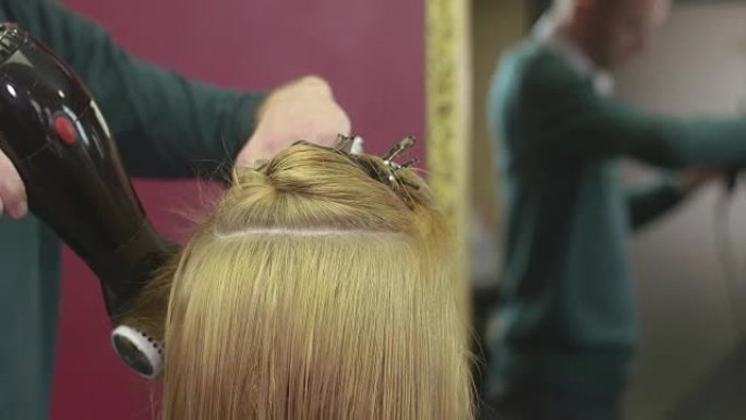 理发师风格的女孩头发在美容沙龙用梳子和吹风机。制作体积发型。镜子
