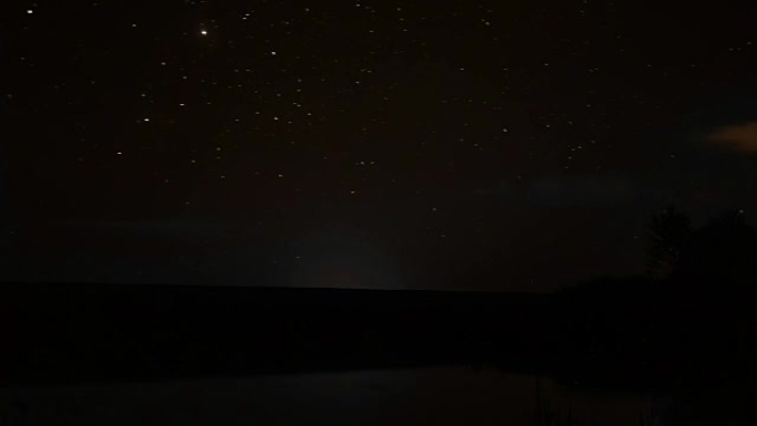 岩石河上夜空中旋转的星星和湖上夜晚的日出旋转的视频大自然睡觉，时光流逝的黄昏，美丽的星星夜晚的流星旋