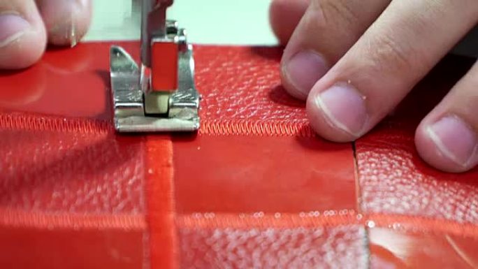 概念工厂生产真皮商品。在缝纫机上缝合红色皮革特写