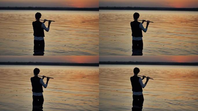 站在水中的夕阳中演奏的长笛演奏家的剪影