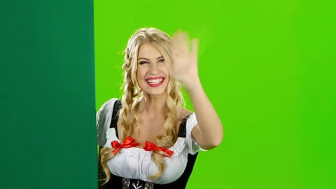 穿着巴伐利亚民族服装的女人挥舞着。绿屏