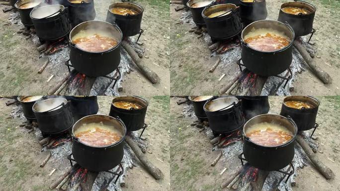 木火上的传统大锅。炖肉由肉，辣椒，西红柿制成。加水。一个男人正在用木勺在锅里搅拌肉