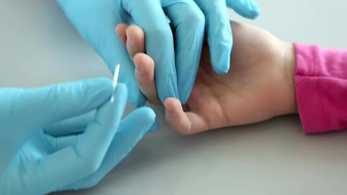 护士在医学实验室从孩子的手指上取血