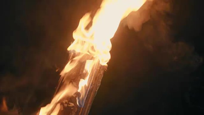 一个人的手在火炬的帮助下放火烧木头。火灾特写