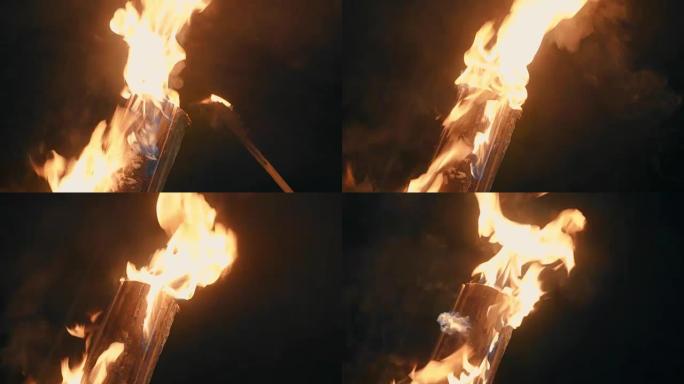 一个人的手在火炬的帮助下放火烧木头。火灾特写
