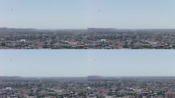 直升机在洛杉矶贝弗利山地区上空飞行。轻型直升机着陆进场。直升机斜向下降，以市中心建筑为背景。警察直升