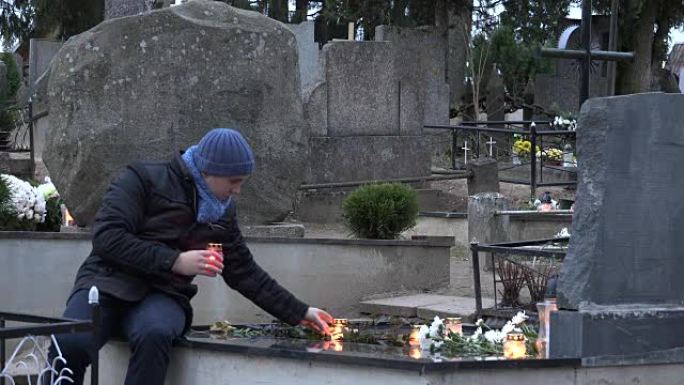 神父在墓地的女儿儿子坟墓上蜡烛。