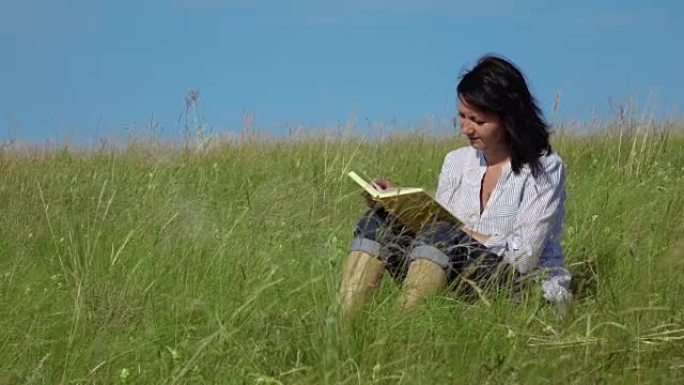 一名妇女在绿色草坪上阅读的慢动作视频