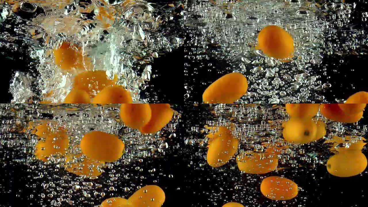许多橙色金橘落入水中超级慢动作视频。黑色背景