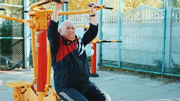 老人在公共户外健身房用健身器材锻炼。
