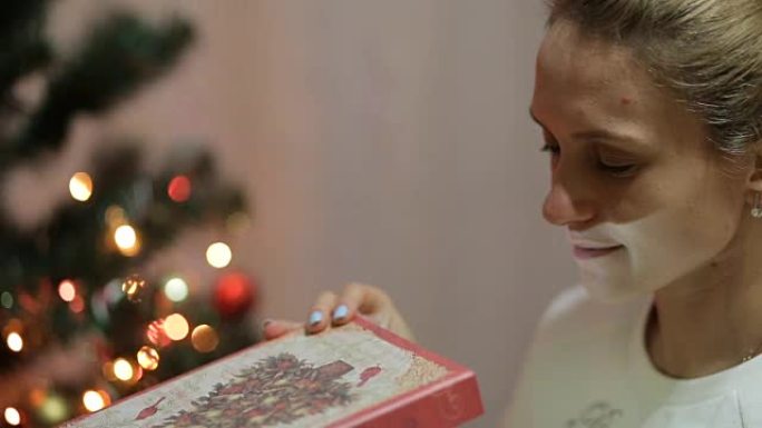 年轻美女少女打开圣诞礼品盒与奇迹。圣诞节和新年树。惊讶快乐的女人得到了魔法礼物。