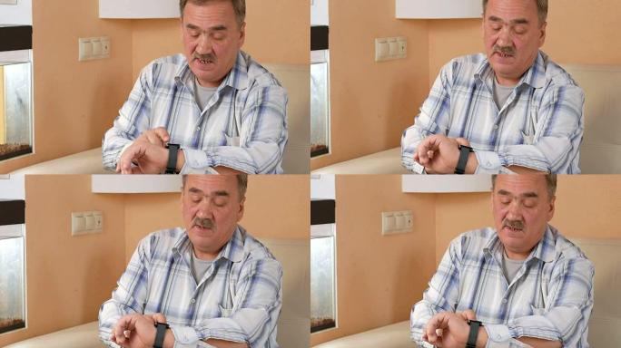 老人胡子在家里检查智能手表上的信息。他坐在水族馆附近的沙发上，发出消息