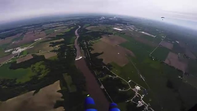 专业跳伞运动员在绿色平地上方的灰色天空中打开降落伞。景观