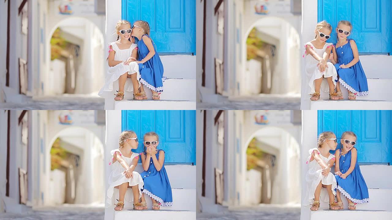 可爱的小女孩在希腊米克诺斯岛上典型的希腊传统村庄的街道上，白色的墙壁和五颜六色的门