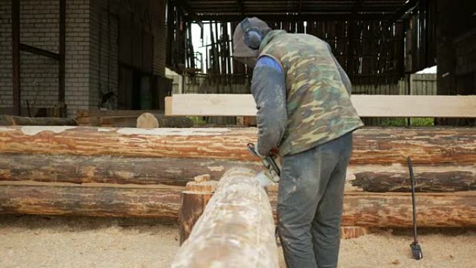 男人为未来的家切割木锯。建筑工人脸上的防护面罩和大量木屑。机库，背景是未来家园的一部分