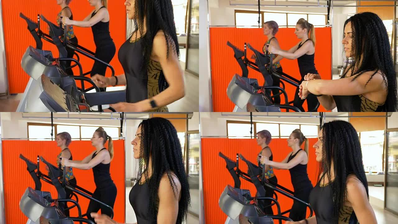 深色皮肤的女人在跑步机上慢跑时在智能手表上使用活动健身跟踪器应用程序