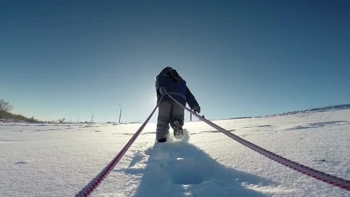 小孩拉雪橇到坡顶