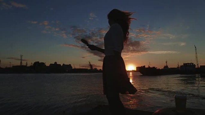 女人在日落河港口梳头跳舞