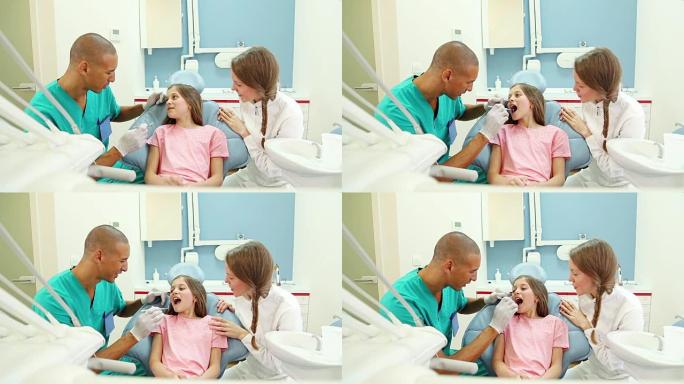 微笑的年轻女孩与牙医和外科医生交谈，显示出她的牙齿酸痛