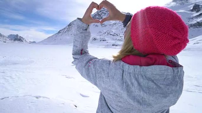 滑雪场上的年轻女子塑造心形