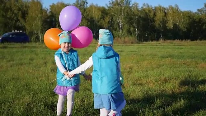 快乐的孩子们拿着气球在公园里手牵着手盘旋。露天儿童假期