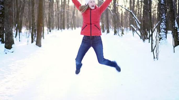冬季公园里迷人的年轻女子，跳起来滑稽而愚蠢，开心，微笑。慢动作