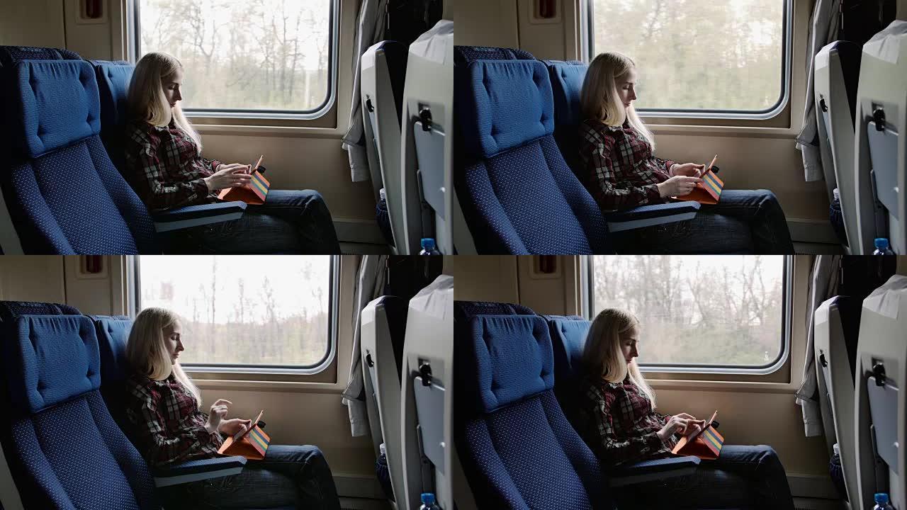 年轻女子乘火车旅行时在彩色盒子里使用平板电脑
