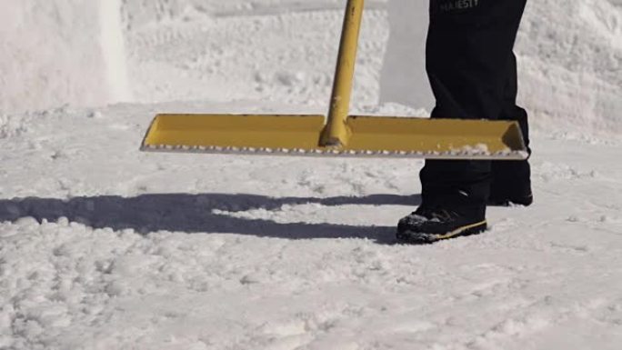 男子在滑雪胜地用铁锹清除斜坡上的雪。晴天。喷涂。雪堆