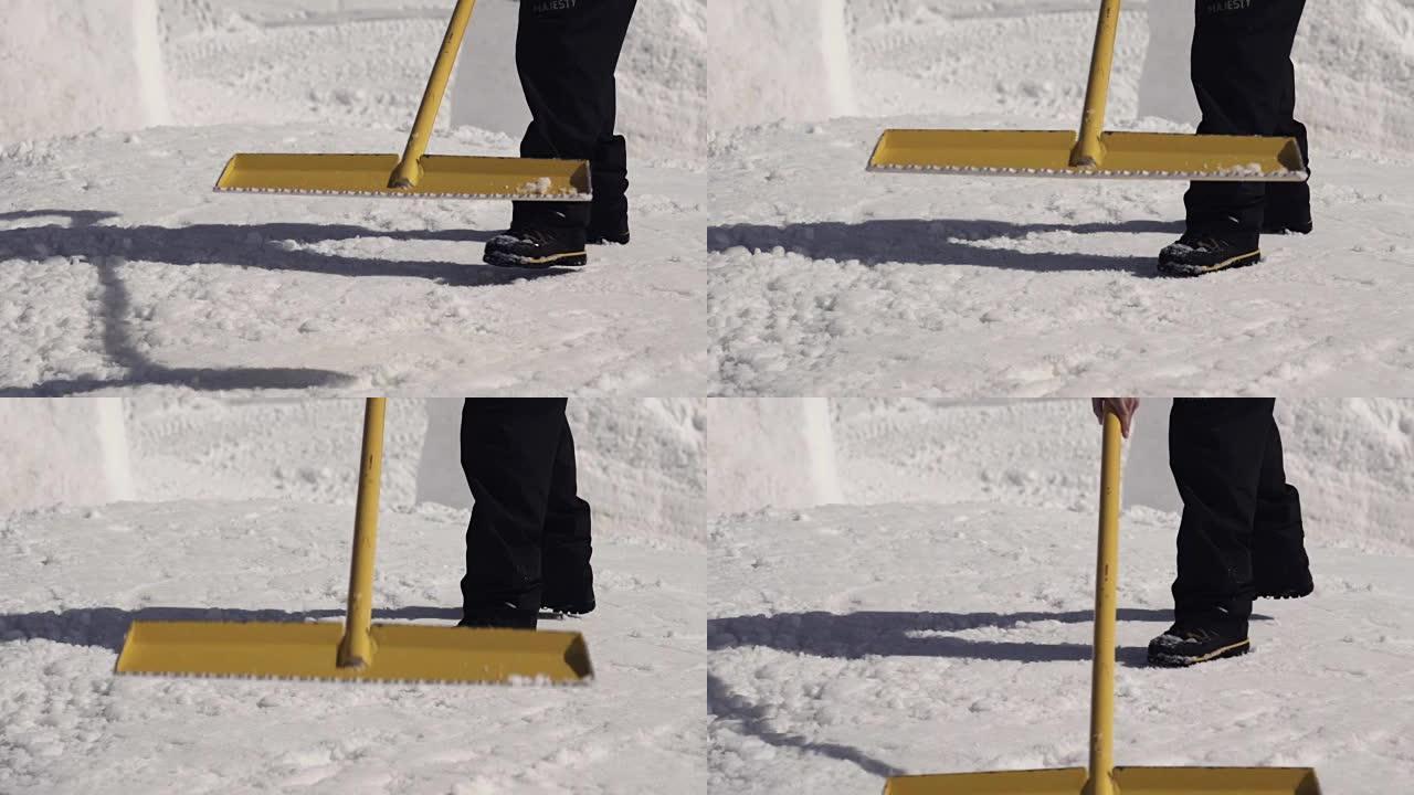男子在滑雪胜地用铁锹清除斜坡上的雪。晴天。喷涂。雪堆