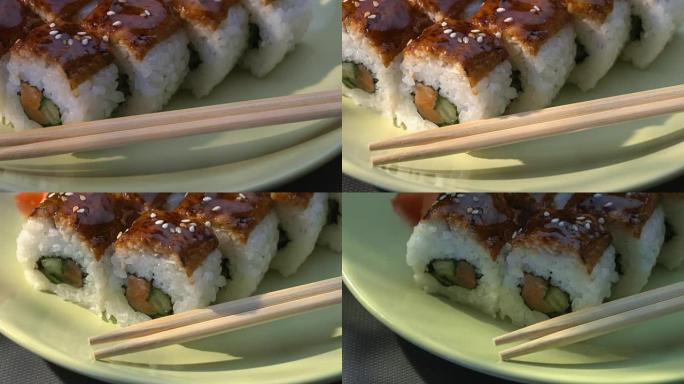 开胃的惊人的 “龙” 方形寿司卷，鳗鱼，鲑鱼，黄瓜，紫菜，寿司饭，芝麻。盘。筷子、腌制生姜和芥末。特