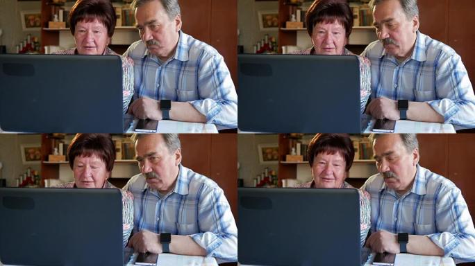 一对老年夫妇正坐在家里的笔记本电脑旁。一个女人读新闻，一个留着小胡子的男人坐在他旁边说话