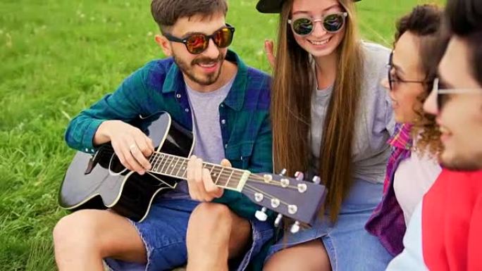 一群年轻英俊的人在野餐时，他们弹吉他和唱歌。