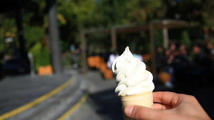 一个男人在模糊的城市街道的背景下吃快餐冰淇淋。