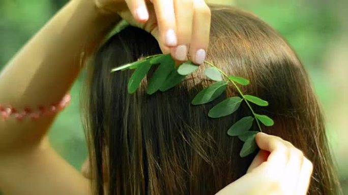 年轻的黑发女人在森林的头发中插入叶子