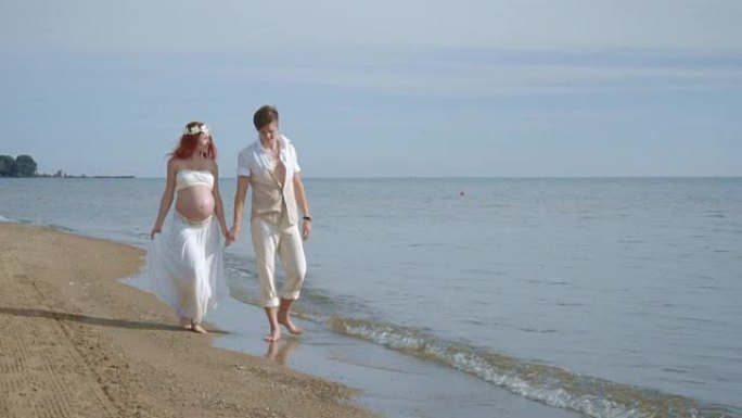 夫妇步行海滩。海边的怀孕夫妇。海滩上的孕妇