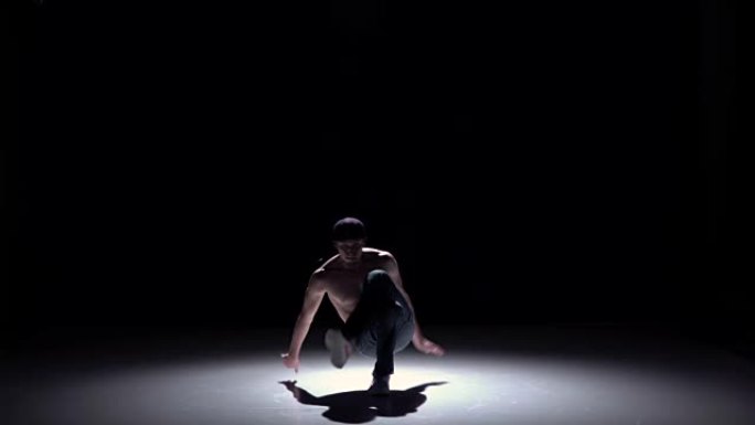 霹雳舞男子从坐着的姿势跳舞黑色，阴影，慢动作