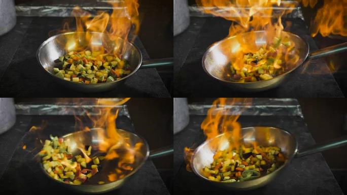厨师油炸蔬菜。白兰地在锅里点燃。在厨房里开火