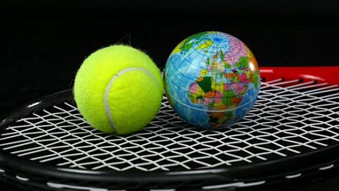手将一个网球和一个带有地球仪的球放在黑底网球拍上