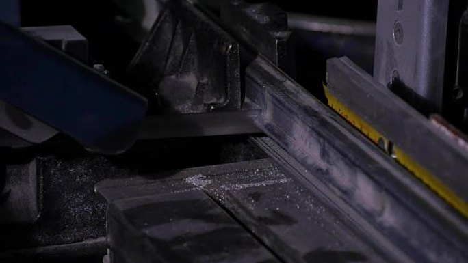用冷却剂加速工业带锯条的动作镜头，显示运动模糊。带锯条的冷冻动作镜头显示牙齿和冷却剂。带锯机在工作。