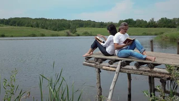 湖附近的木板桌上的男人和女人看书