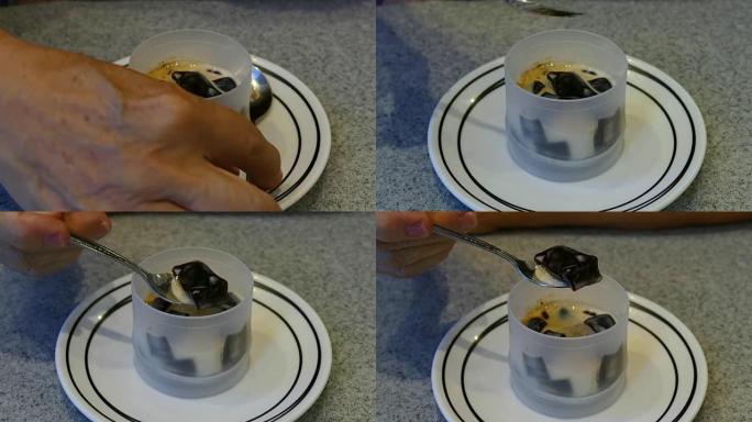 女人的手用勺子吃咖啡果冻甜点