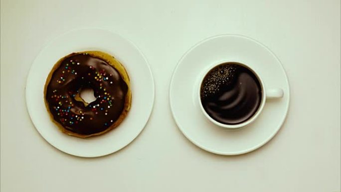停止动作，动画。盘子上的甜甜圈和一杯茶碟上的咖啡。顶视图