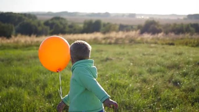 快乐的男孩在公园里带着气球跑步。散步和户外娱乐