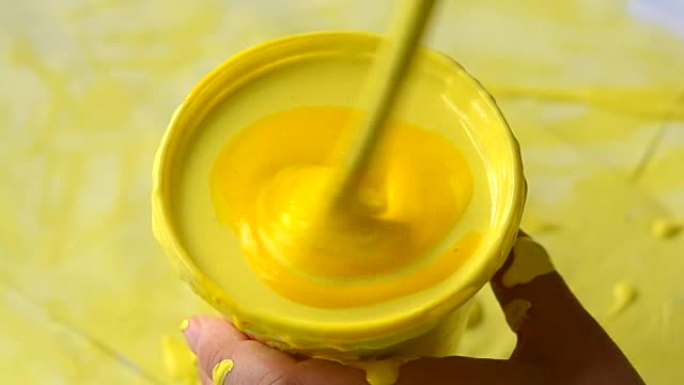 在带有黄色油漆的塑料烧杯中倒入黄色颜料并混合
